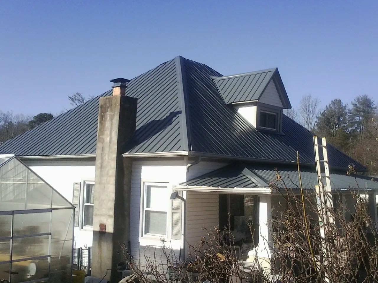 Dark blue standing seam metal roof on a white farmhouse with dormer — Slate & Tile Roof Repair by Roofing Brothers in Upperco