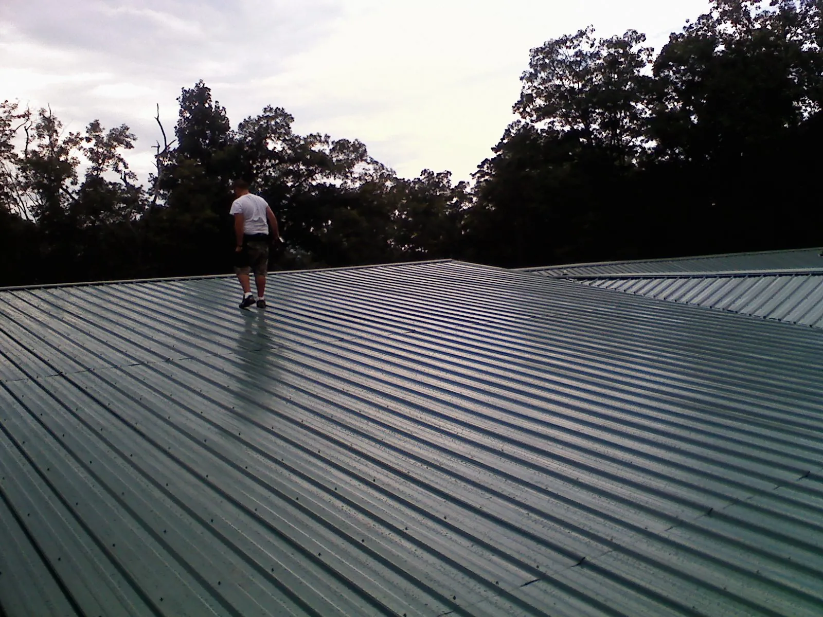Roofer walking a wide expanse of new green metal roofing in Upperco