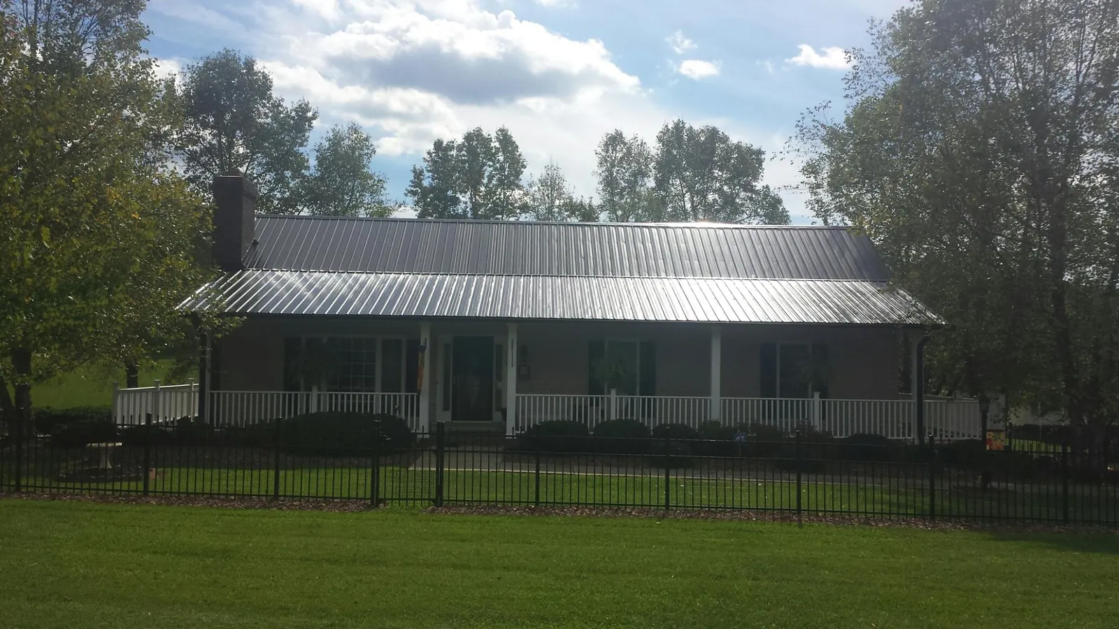 Gray metal roof on a brick ranch with a full width front porch — Gutter Guard Installation work by our crew in Upperco