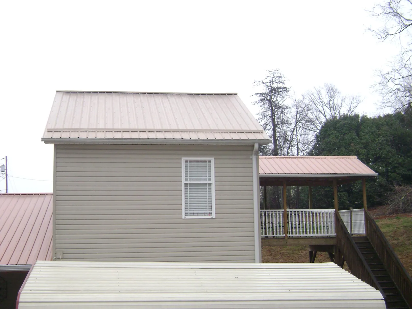 Tan metal roofs on a two story addition and attached porch, from a Roof Replacement job in Upperco