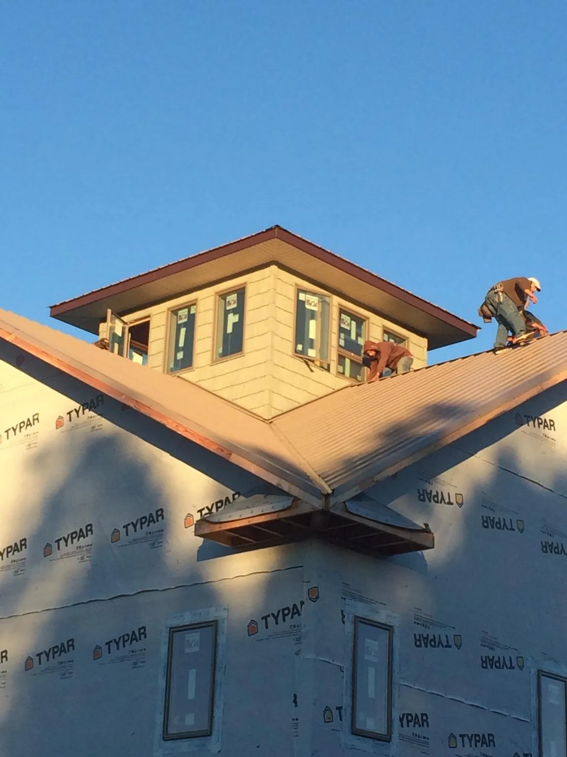 Roofers working around a rooftop cupola on a new metal roof at sunset — Roof Waterproofing in Upperco by Roofing Brothers